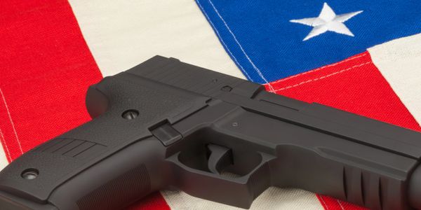 A black handgun resting on a folded American flag.