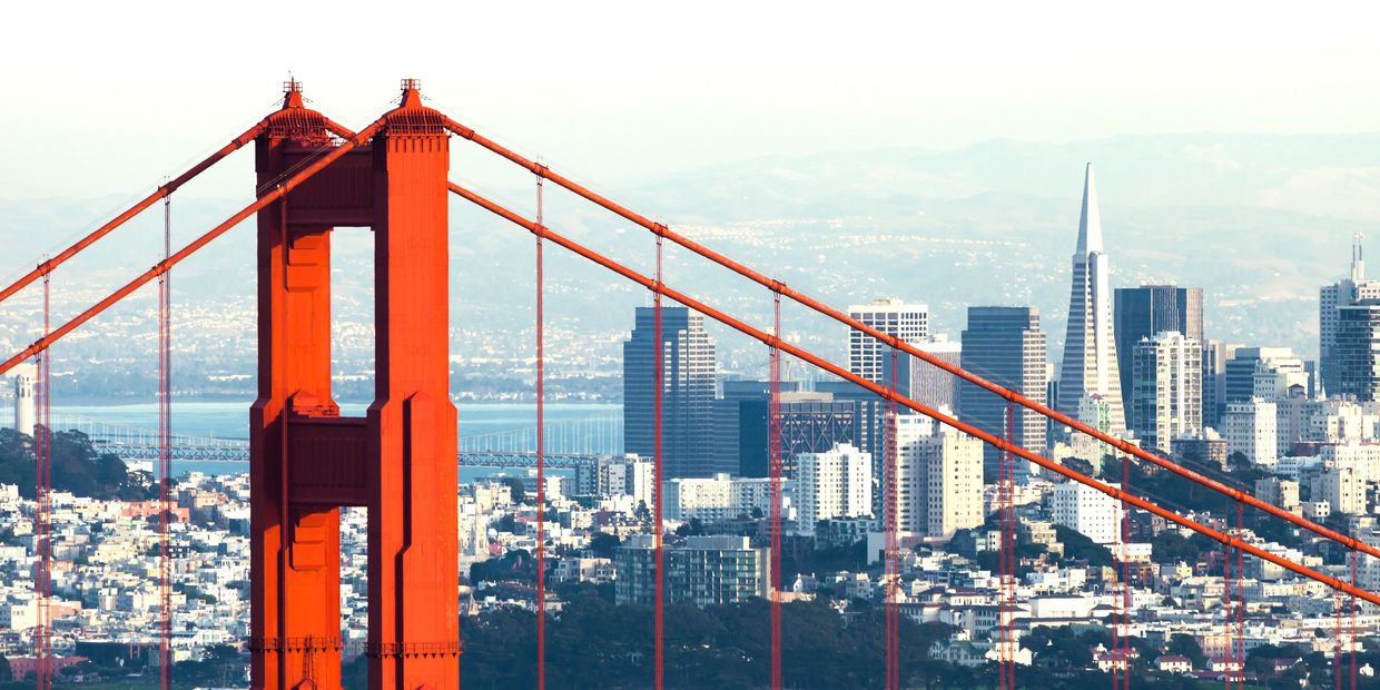 Golden Gate Bridge tower with San Francisco skyline in the background.