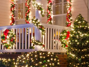Porch decorated with Christmas lights, wreaths, and garlands.
