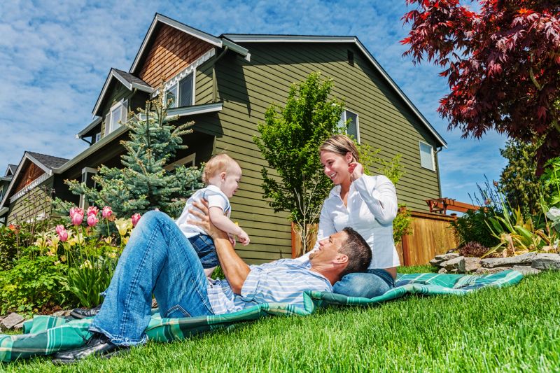 Photo of a happy family in front of their home, enjoying a sunny day in the yard on a blanket.