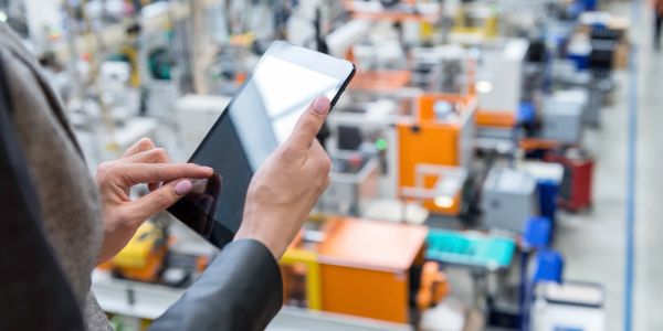 Person using a tablet in an industrial factory setting.