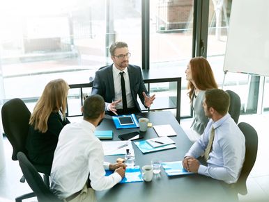 Business meeting with five professionals discussing strategy at a conference table.