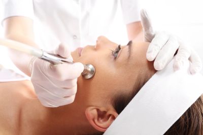 Woman receiving a facial treatment with a beauty device.