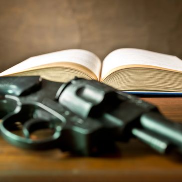 Revolver and open book on wooden surface.