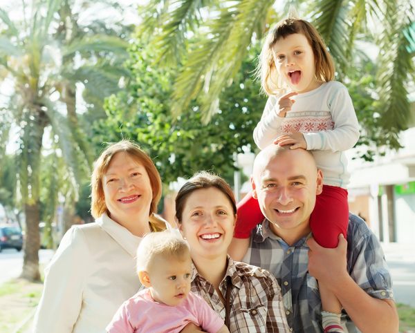 Happy family posing outdoors with palm trees in the background.