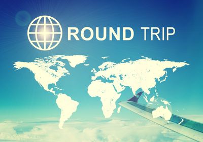Round trip travel concept with world map and airplane wing.