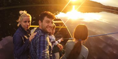 Family enjoying a serene sunset boat ride on a calm lake.