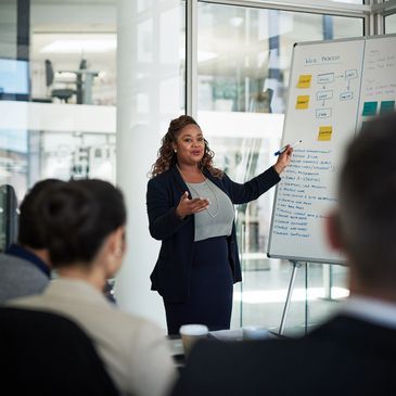 Businesswoman presenting a web process flowchart to colleagues in a meeting.