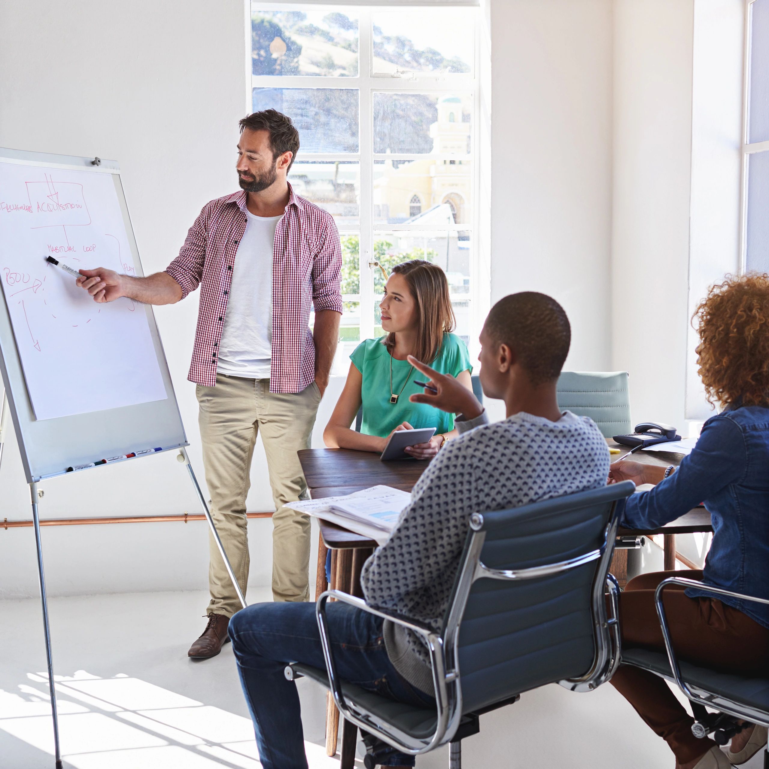 Man presenting ideas to a diverse team in a bright office meeting.