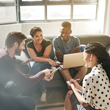 A group of four young professionals collaborating in a bright, casual office setting.