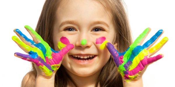 Happy child with colorful paint on hands and face.