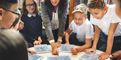 Teacher and students engaged in a group learning session using tablets in a library.