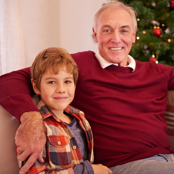 Grandfather and grandson smiling together by a Christmas tree.