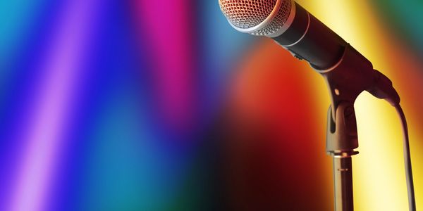 A microphone on a stand with colorful blurred lights in the background.