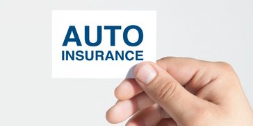 Hand holding a card with 'AUTO INSURANCE' text.
