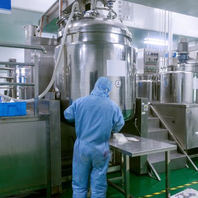 A worker in blue protective gear operates machinery in a clean industrial facility.