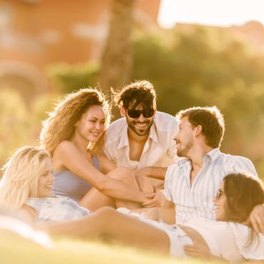 Group of friends enjoying a sunny day outdoors, smiling and relaxing.