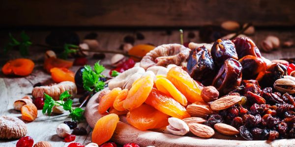 Assorted dried fruits and nuts arranged on a rustic wooden surface.