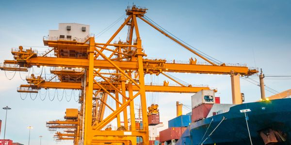 Large yellow cranes unloading containers at a busy port.