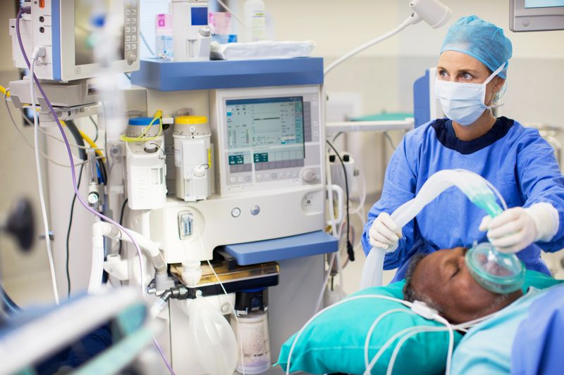 Female doctor wearing surgical clothing anesthetizing patient in operating theater