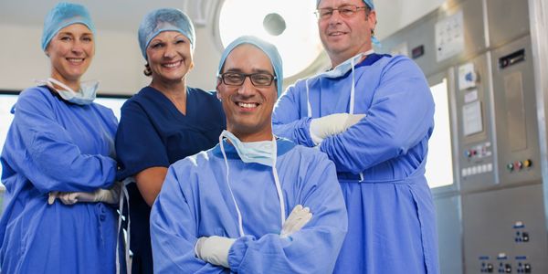 Group of smiling medical professionals in scrubs and caps.