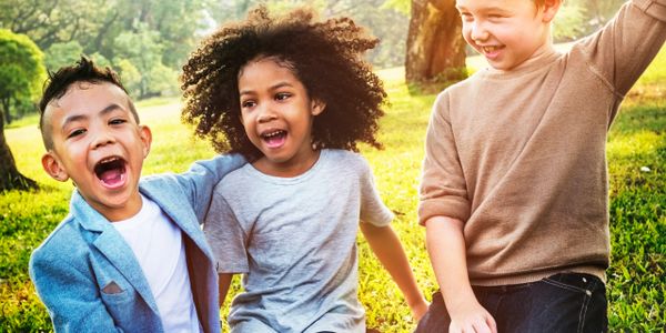 Three children joyfully playing outdoors on a sunny day.