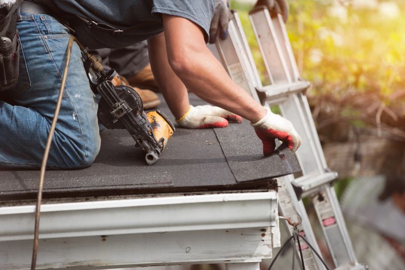 roofers installing a new roof on residential home. weatherlock material and brown asphalt roofing shingles