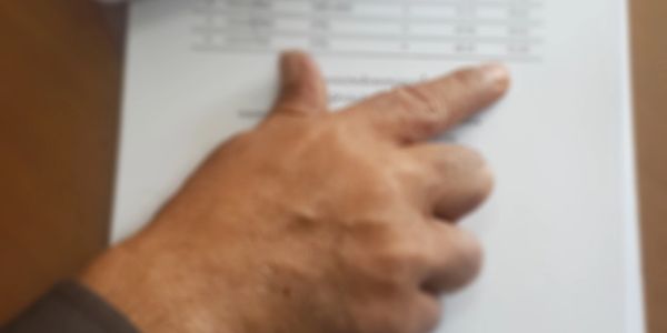 A hand pointing at a document with printed text.