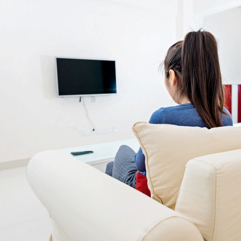 Young woman watching TV at home.