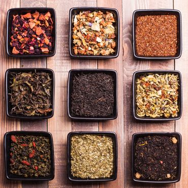 Nine square bowls with different loose leaf teas arranged in a grid.