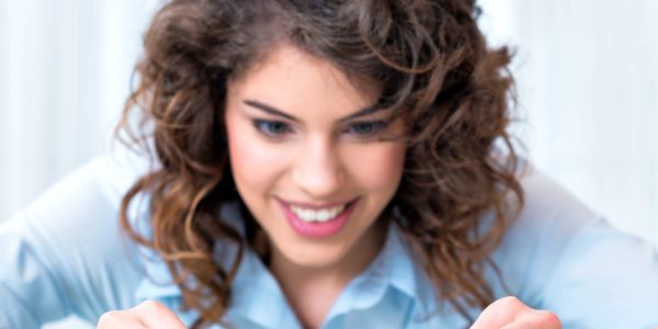 A woman with curly hair smiling while looking down.