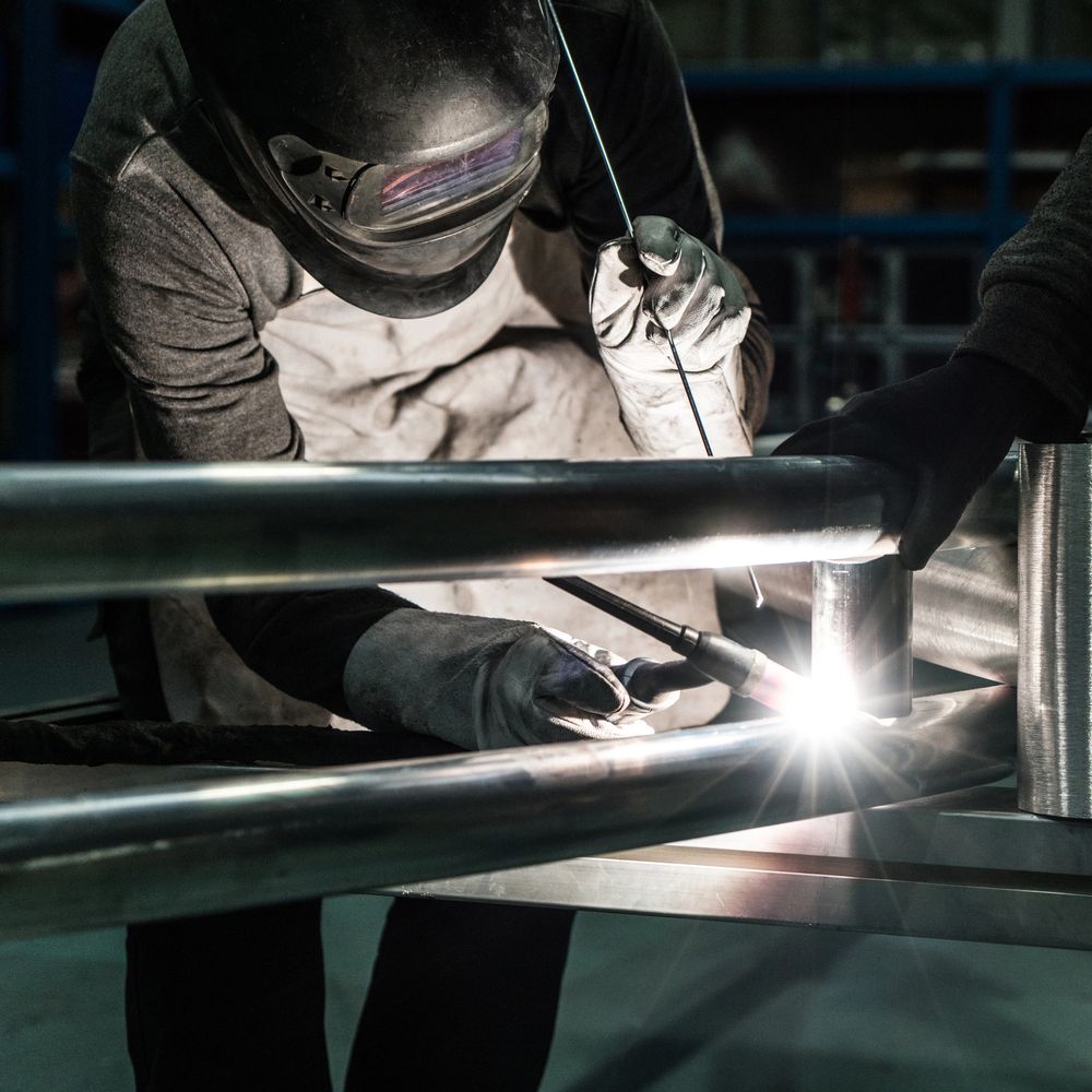 A welder working on a metal frame with protective gear.