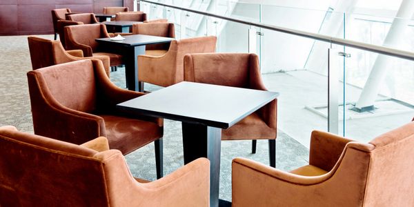 Modern seating area with brown chairs and black tables near glass railing.