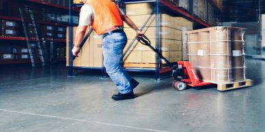 Warehouse worker moving a pallet with a hand pallet jack.