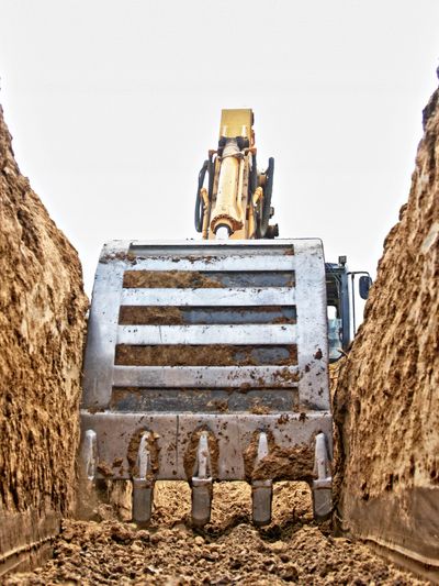 Close-up of an excavator bucket digging a trench.