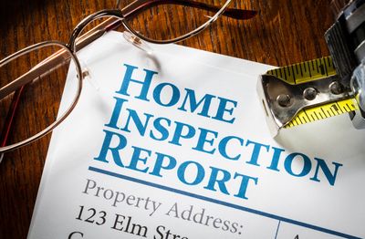 Close-up of a home inspection report with glasses and a measuring tape.