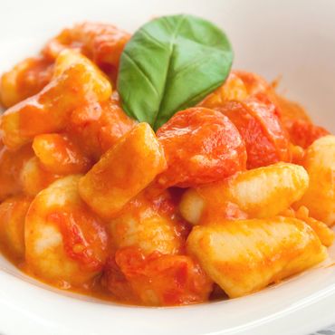 Plato de ñoquis a la Sorrentina con salsa de tomate, mozzarella, queso parmesano y albahaca.