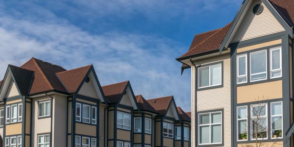 Row of modern townhouses under a blue sky.