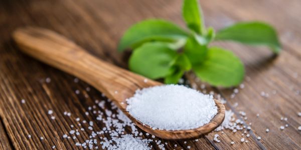 Wooden spoon with salt and green leaves.