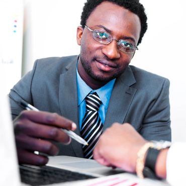 Businessman in suit and glasses discussing with a client in an office.