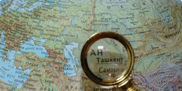 Magnifying glass over Tashkent on a map.