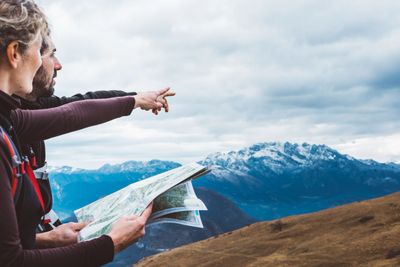 Two hikers studying a map with snowy mountains in the background.