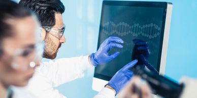Scientists in a lab analyzing DNA data on a computer screen.
