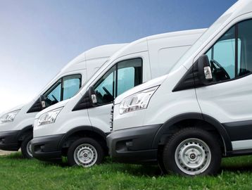 Row of white delivery vans parked side by side.