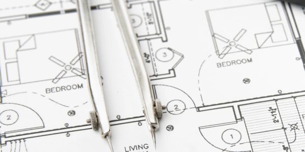 Architectural blueprint with a metal compass tool on top.