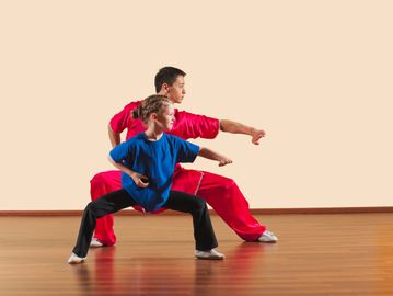 Martial arts instructor teaching a young girl in a studio.