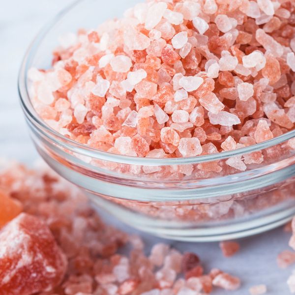 A glass bowl filled with pink Himalayan salt crystals.