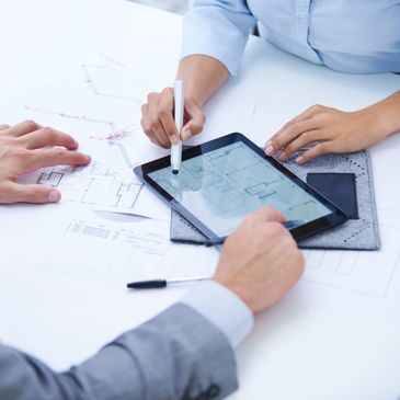 Two people discussing architectural plans using a tablet and printed blueprints.