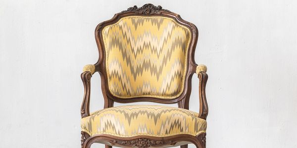 Antique wooden armchair with yellow patterned upholstery.