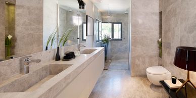 Modern bathroom with marble surfaces, large mirror, and glass shower enclosure.